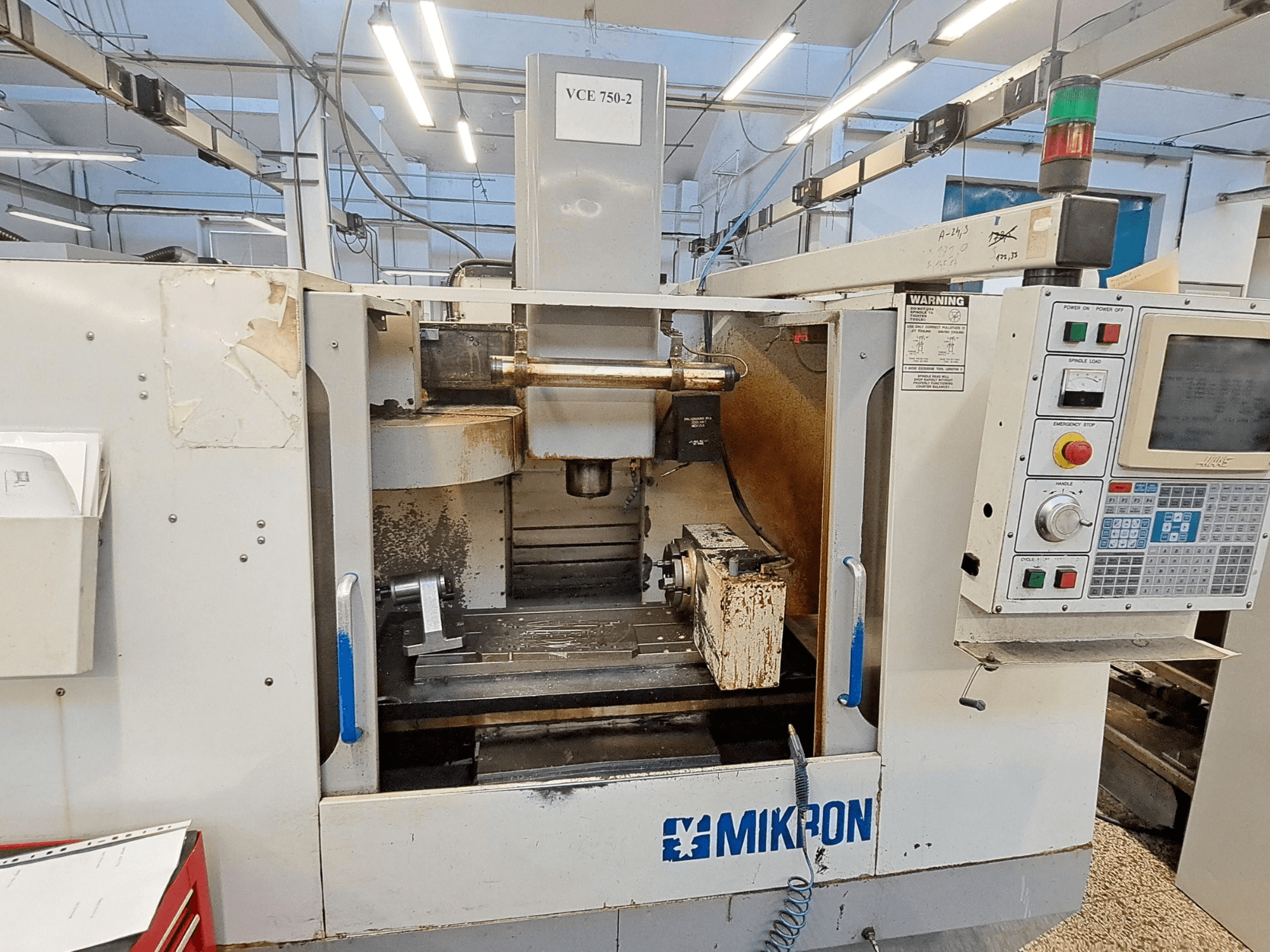 Mikron VCE 750-2 CNC-Fräsmaschine, Vorderansicht, mit Bedienfeld und Spindel im Bearbeitungsbereich, zeigt Verschleiß und Verschmutzung.
