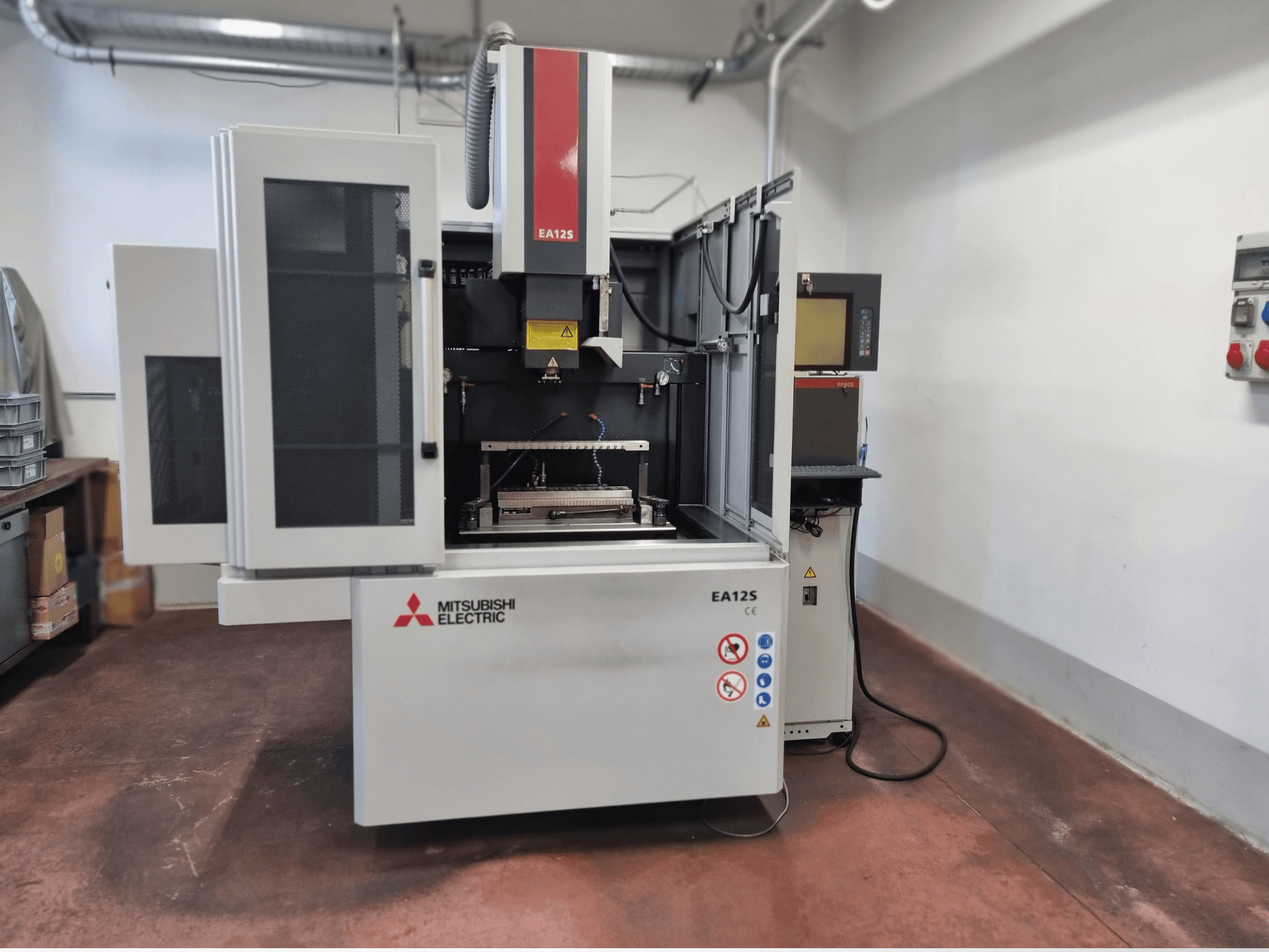 Mitsubishi Electric EA12S Drahtschneidemaschine, Vorderansicht, mit offenen Türen, Bedienfeld und Sicherheitsschildern.