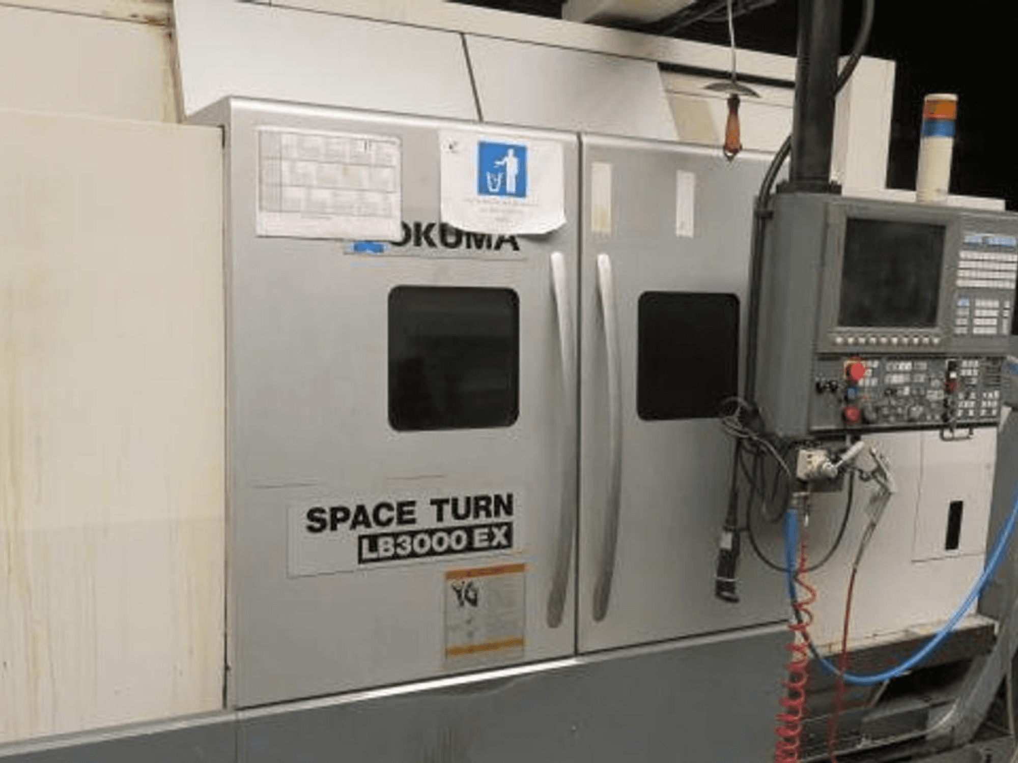Okuma Space Turn LB3000 EX CNC-Drehmaschine, Seitenansicht, mit Bedienfeld, zwei Türen und sichtbarer Verkabelung.