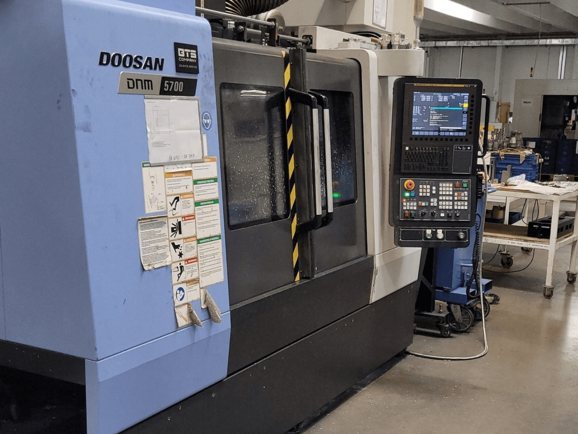 Vertikales Bearbeitungszentrum DOOSAN DNM 5700, Vorderansicht, mit Blick auf das Bedienfeld und die Bedienelemente.